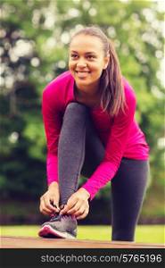 sport, exercise, park and lifestyle concept - smiling african american woman exercising outdoors