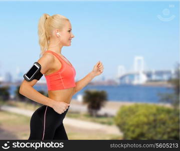 sport, exercise, technology, internet and healthcare - smiling sporty woman running and listening to music from smartphone