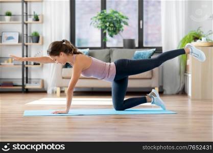 sport, fitness and exercising concept - happy young woman doing elbow knee crunches at home. young woman exercising and doing sports at home
