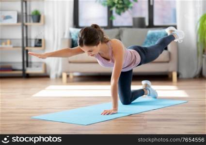 sport, fitness and exercising concept - happy young woman doing elbow knee crunches at home. young woman exercising and doing sports at home