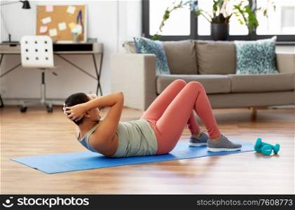 sport, fitness and healthy lifestyle concept - african american woman doing abdominal exercises or crunches at home. african woman doing abdominal exercises at home