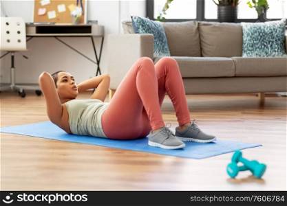 sport, fitness and healthy lifestyle concept - african american woman making abdominal exercises or crunches at home. african woman making abdominal exercises at home