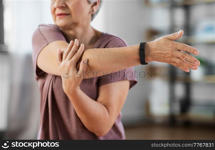 sport, fitness and healthy lifestyle concept - close up of senior woman exercising on mat and stretching arm at home. close up of senior woman exercising at home