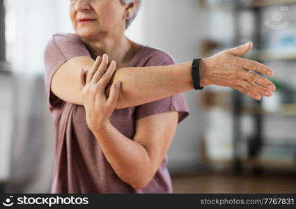 sport, fitness and healthy lifestyle concept - close up of senior woman exercising on mat and stretching arm at home. close up of senior woman exercising at home