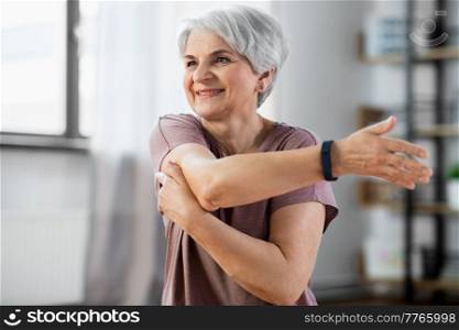 sport, fitness and healthy lifestyle concept - close up of smiling senior woman exercising on mat and stretching arm at home. close up of senior woman exercising at home