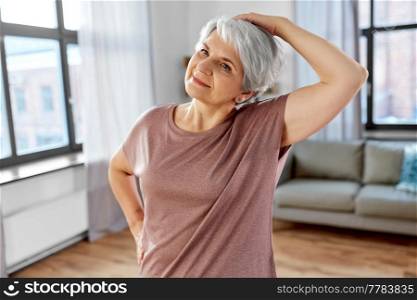 sport, fitness and healthy lifestyle concept - close up of smiling senior woman exercising on mat and stretching neck at home. close up of senior woman exercising at home