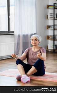 sport, fitness and healthy lifestyle concept - happy senior woman meditating on exercise mat at home. happy senior woman meditating on mat at home