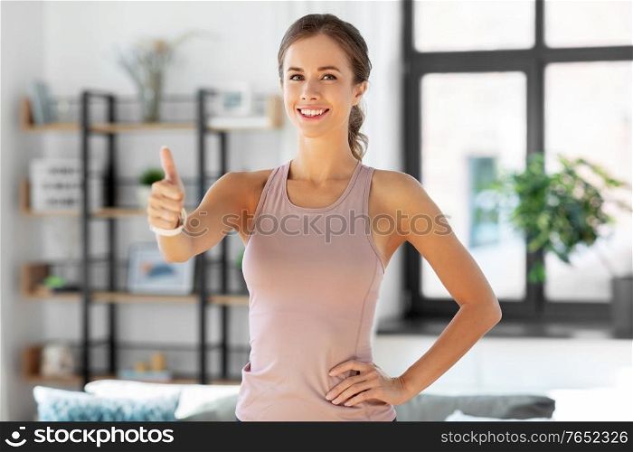 sport, fitness and healthy lifestyle concept - happy smiling woman showing thumbs up at home. sporty smiling woman showing thumbs up at home