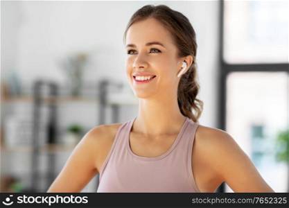 sport, fitness and healthy lifestyle concept - happy smiling woman with earphones exercising at home. smiling woman with earphones exercising at home
