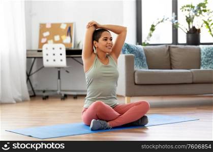 sport, fitness and healthy lifestyle concept - happy smiling young african american woman stretching arm at home. african american woman stretching arm at home