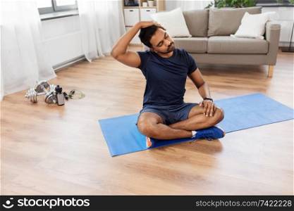 sport, fitness and healthy lifestyle concept - indian man training and stretching body at home. man training and stretching body at home