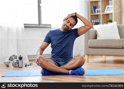 sport, fitness and healthy lifestyle concept - indian man training and stretching body at home. man training and stretching body at home