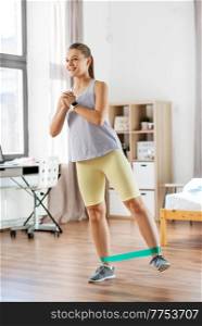 sport, fitness and healthy lifestyle concept - legs of young woman or teenage girl exercising with resistance band at home. woman exercising with resistance band at home