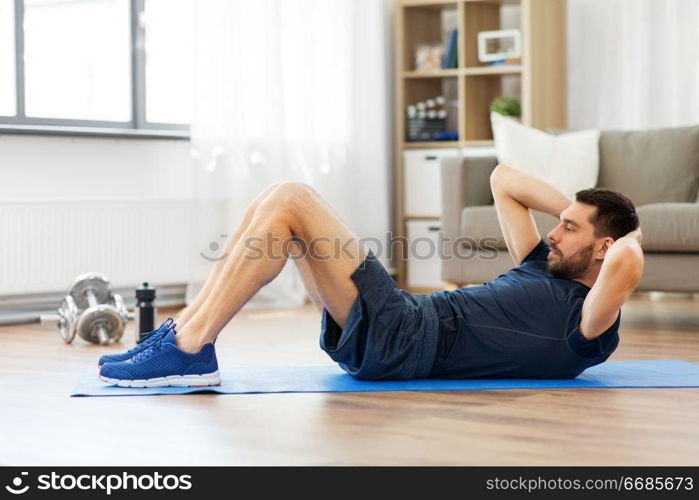 sport, fitness and healthy lifestyle concept - man making abdominal exercises at home. man making abdominal exercises at home