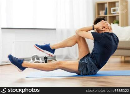 sport, fitness and healthy lifestyle concept - man making bicycle crunch on exercise mat and flexing abs at home. man making bicycle crunch exercise at home