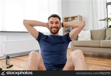 sport, fitness and healthy lifestyle concept - smiling man making abdominal exercises at home. smiling man making abdominal exercises at home