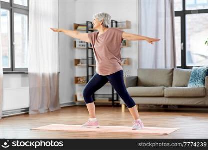 sport, fitness and healthy lifestyle concept - smiling senior woman exercising on yoga mat at home. happy senior woman exercising on yoga mat at home