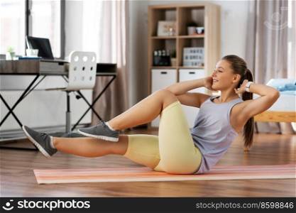 sport, fitness and healthy lifestyle concept - smiling teenage girl exercising on yoga mat at home. happy teenage girl exercising on yoga mat at home