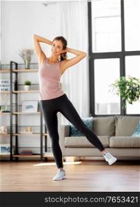 sport, fitness and healthy lifestyle concept - smiling young woman exercising at home. smiling young woman exercising at home