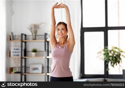 sport, fitness and healthy lifestyle concept - smiling young woman stretching arms at home. smiling young woman stretching arms at home
