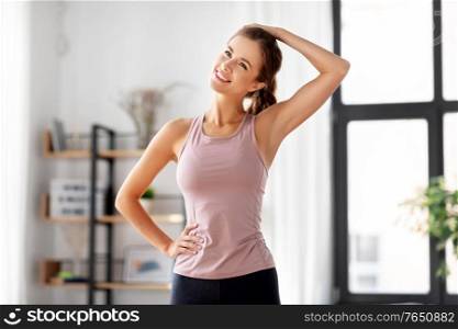 sport, fitness and healthy lifestyle concept - smiling young woman stretching neck at home. smiling young woman stretching neck at home