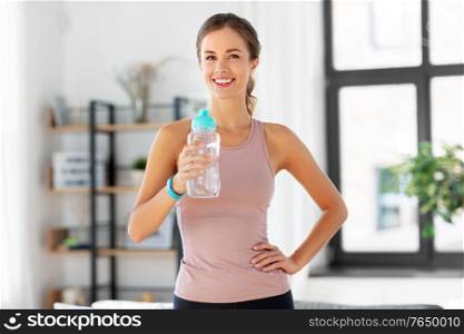 sport, fitness and healthy lifestyle concept - smiling young woman with bottle of water at home. smiling young woman with bottle of water at home