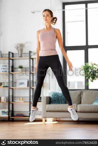 sport, fitness and healthy lifestyle concept - young woman exercising and jumping at home. young woman exercising at home