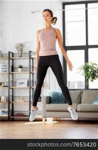 sport, fitness and healthy lifestyle concept - young woman exercising and jumping at home. young woman exercising at home
