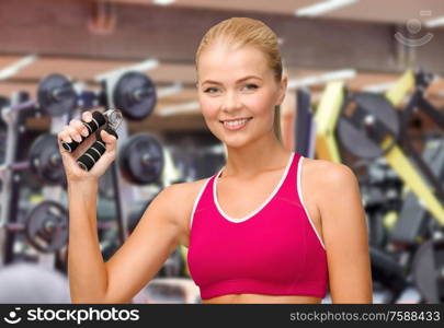 sport, fitness and people concept - beautiful happy smiling woman with hand expander exercising over gym on background. smiling woman with hand expander exercising in gym
