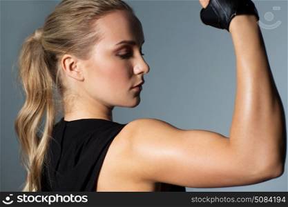 sport, fitness and people concept - close up of young woman posing and showing muscles in gym. close up of woman posing and showing biceps in gym. close up of woman posing and showing biceps in gym