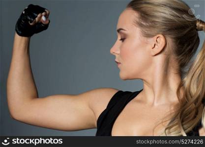 sport, fitness and people concept - close up of young woman posing and showing muscles in gym. close up of woman posing and showing biceps in gym
