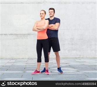 sport, fitness and people concept - happy sportive man and woman over concrete wall background. happy sportive man and woman