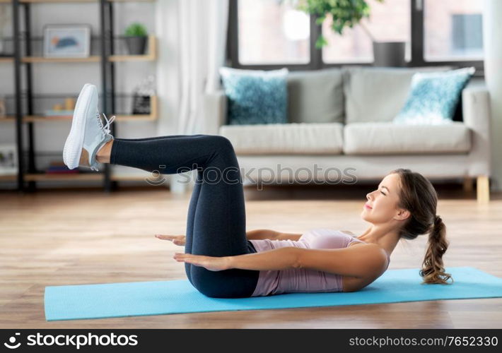 sport, fitness and people concept - happy woman exercising lying on mat at home. woman exercising at home