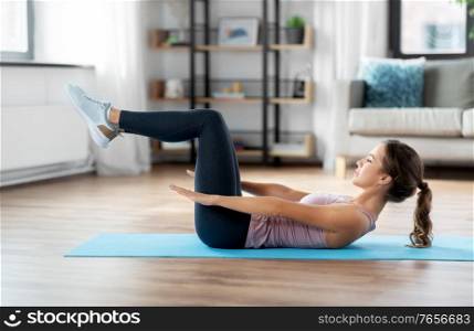 sport, fitness and people concept - happy woman exercising lying on mat at home. woman exercising at home