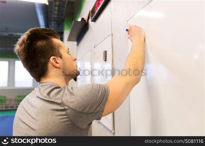 sport, fitness and people concept - man writing note to whiteboard in gym. man writing note to whiteboard in gym