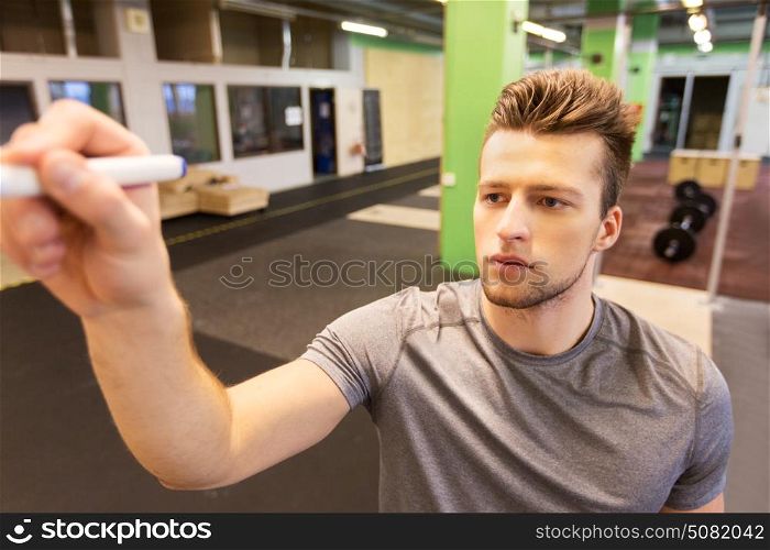 sport, fitness and people concept - man writing note to whiteboard in gym. man writing note to whiteboard in gym