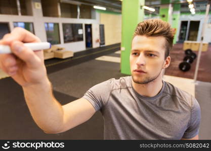 sport, fitness and people concept - man writing note to whiteboard in gym. man writing note to whiteboard in gym