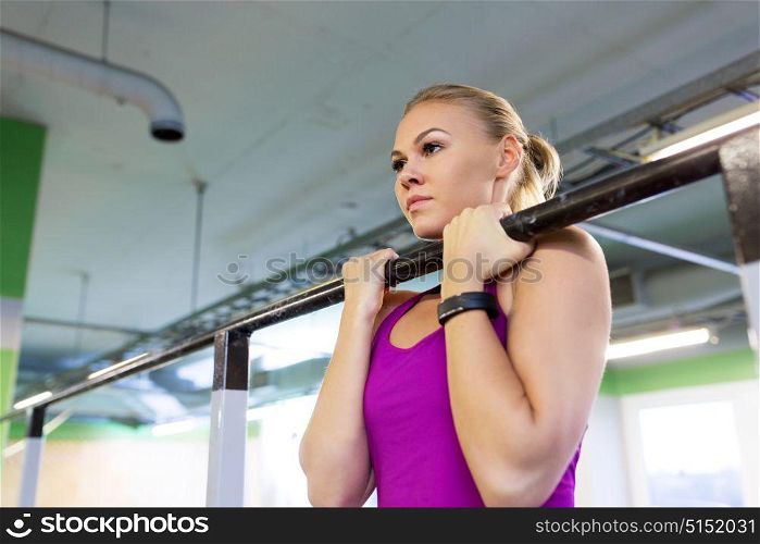 sport, fitness and people concept - woman exercising and doing pull-ups at horizontal bar in gym. woman exercising and doing pull-ups in gym