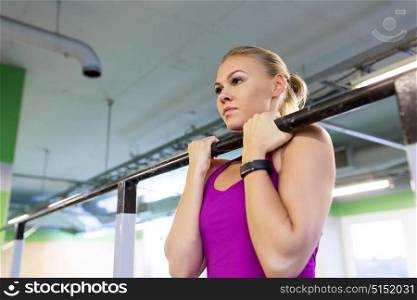 sport, fitness and people concept - woman exercising and doing pull-ups at horizontal bar in gym. woman exercising and doing pull-ups in gym