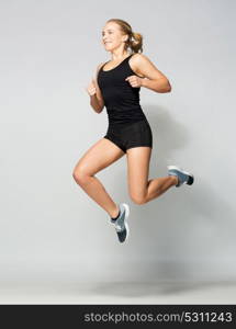 sport, fitness and people concept - young woman in black sportswear jumping in gym. young woman in black sportswear jumping