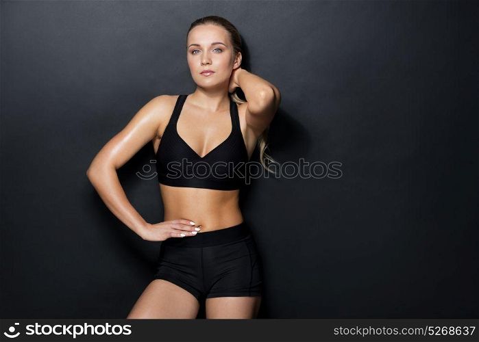 sport, fitness and people concept - young woman in black sportswear posing in gym. young woman in black sportswear posing in gym