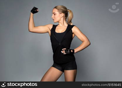 sport, fitness and people concept - young woman posing and showing muscles in gym. young woman posing and showing muscles