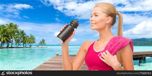sport, fitness and people - happy smiling woman with bottle and towel over tropical beach background in french polynesia. happy smiling woman with sports bottle and towel
