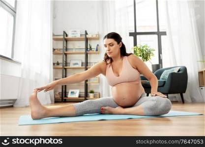 sport, fitness and pregnancy concept - happy pregnant woman exercising at home. happy pregnant woman doing sports at home