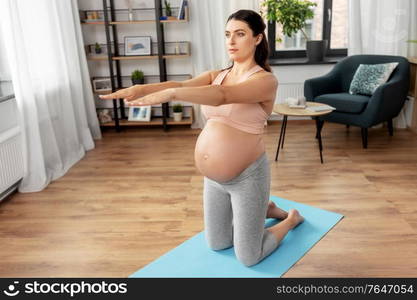 sport, fitness and pregnancy concept - happy pregnant woman exercising at home. happy pregnant woman doing sports at home