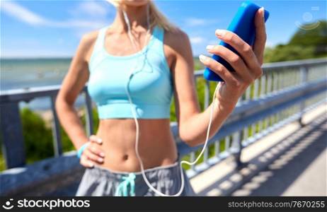 sport, fitness and technology concept - close up of happy smiling sporty young woman with smartphone and earphones. sporty young woman with smartphone and earphones