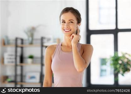 sport, fitness and technology concept - happy smiling woman with earphones exercising at home. smiling woman with earphones exercising at home