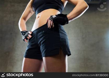 sport, fitness, bodybuilding and people concept - close up of young woman torso and hips in gym