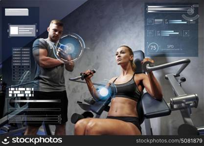 sport, fitness, bodybuilding, exercising and people concept - young woman and personal trainer with smartphone flexing muscles on gym machine over virtual charts. man and woman flexing muscles on gym machine