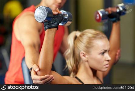 sport, fitness, bodybuilding, lifestyle and people concept - man and woman with dumbbells flexing muscles in gym
